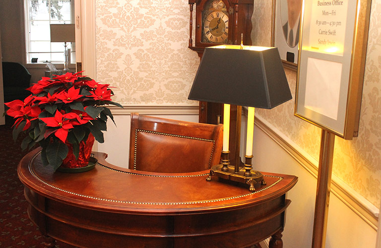 Poinsettia on a wooden desk with lamp in a warmly lit hallway or office nook
