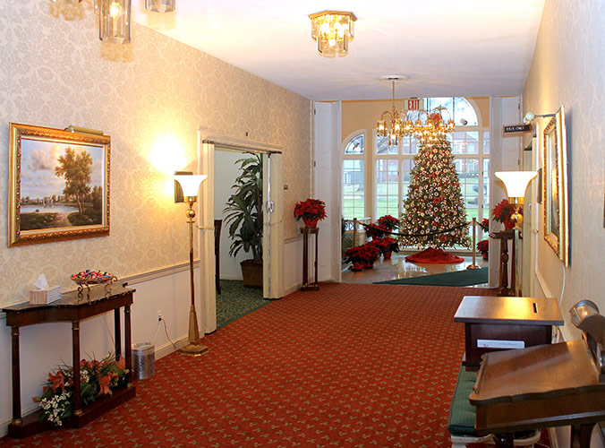 Decorated hotel hallway with a lit Christmas tree and red poinsettias on a red carpet