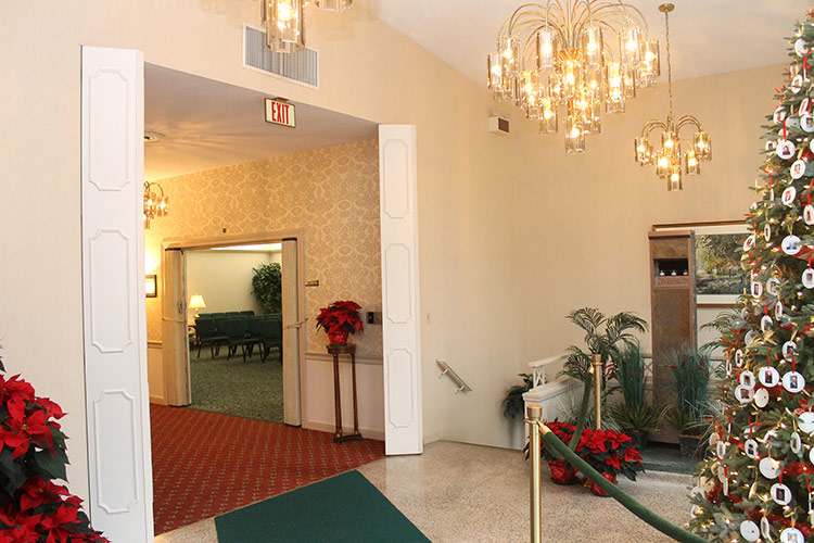 Festive hotel lobby with chandeliers, red poinsettias, and a decorated Christmas tree