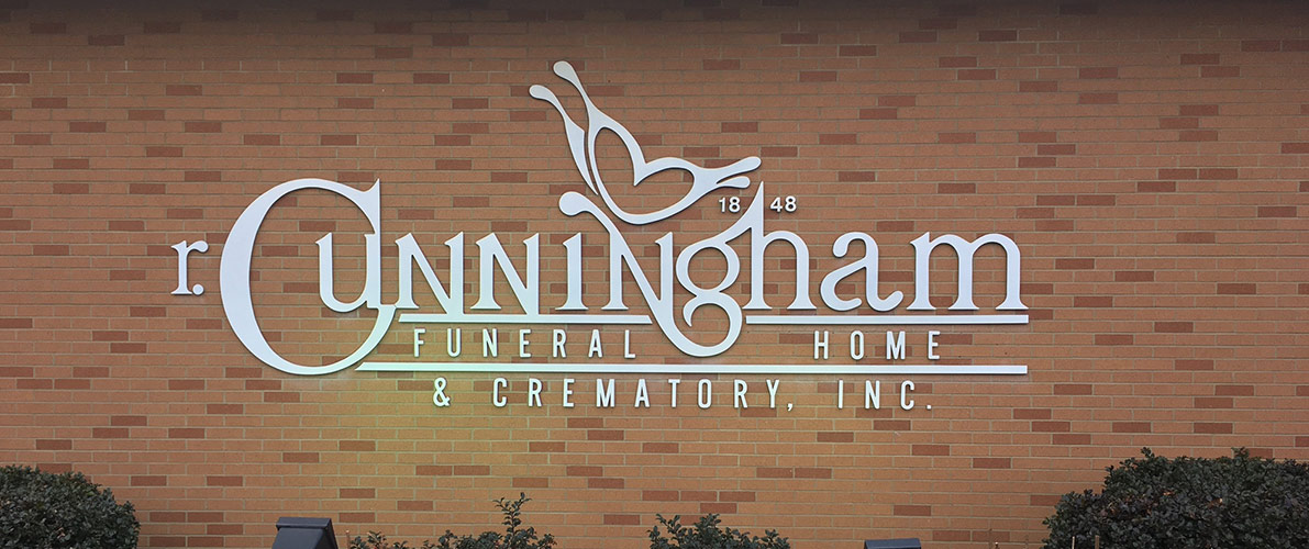 Cunningham Funeral Home sign on a brick wall with white lettering and a bird logo.