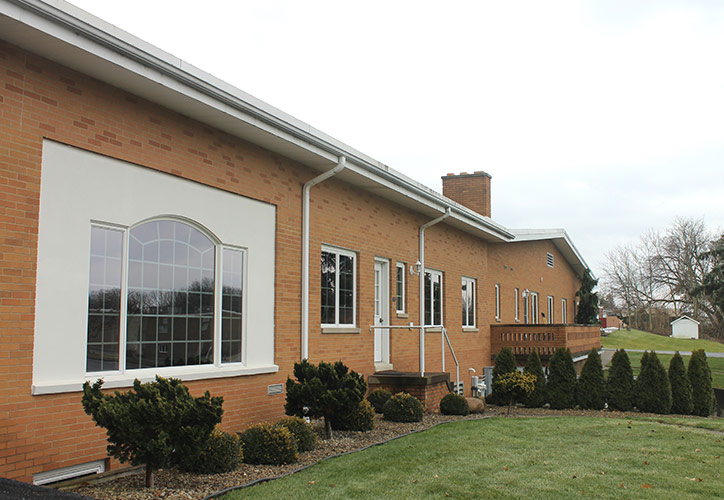 Brick building with large windows and a landscaped lawn on a cloudy day
