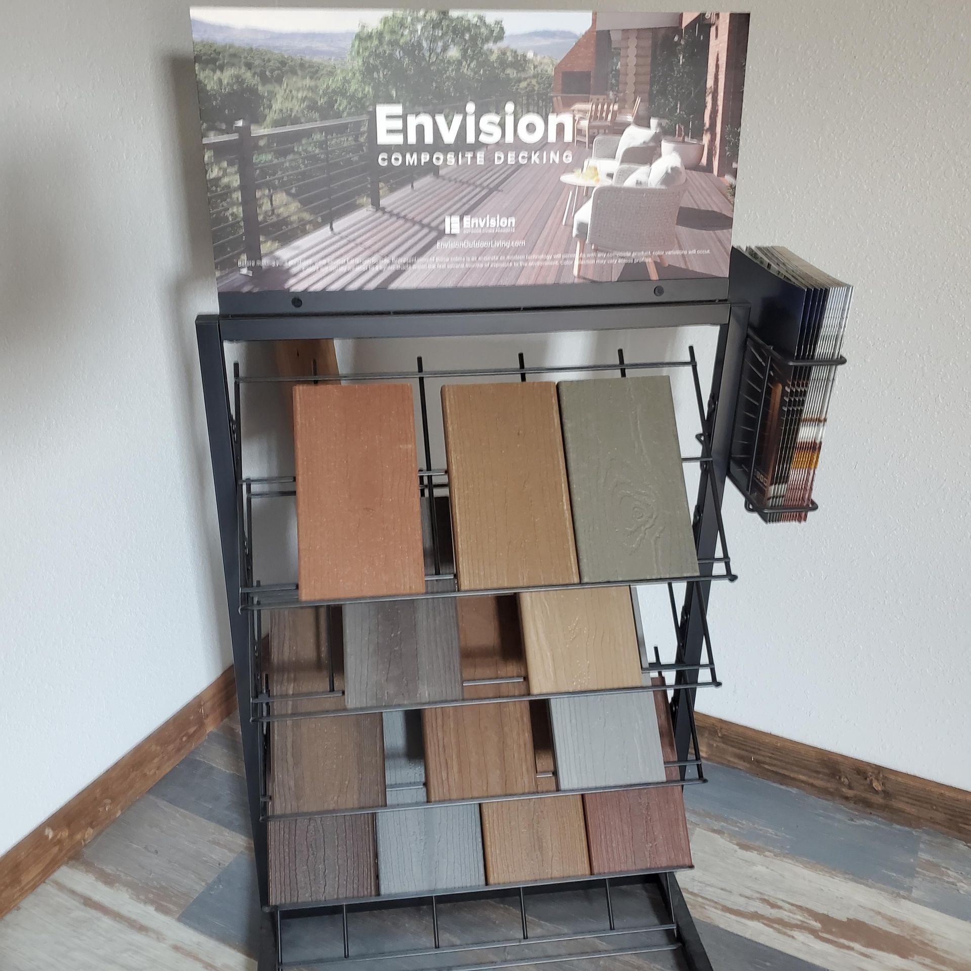 Display rack of flooring samples with Envision Composite Decking sign in a room.