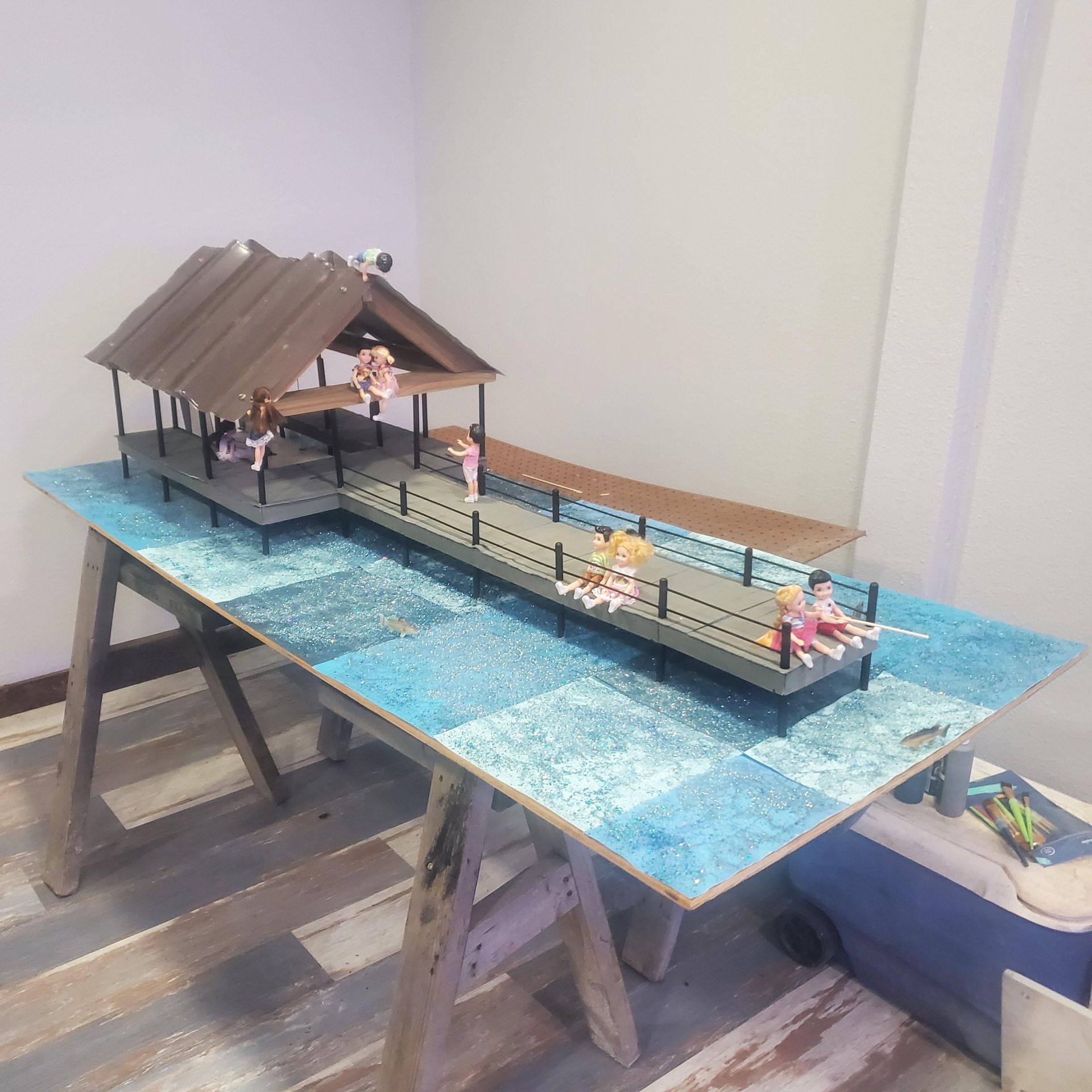 Miniature bridge scene with a blue waterway, pavilion, railings, and tiny figures on a tabletop display