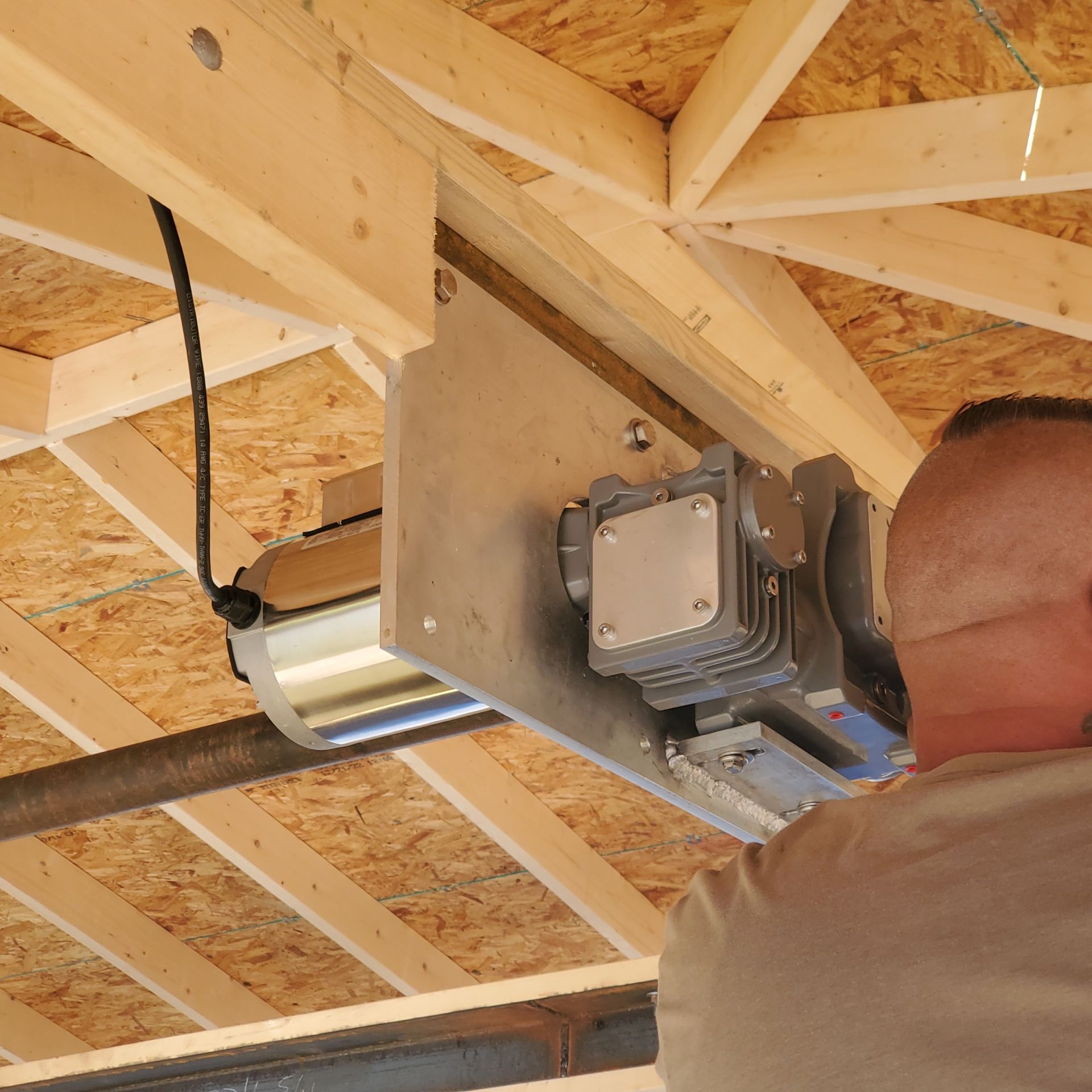 Ceiling-mounted boat lift on unfinished wooden framing, with a person partially visible.