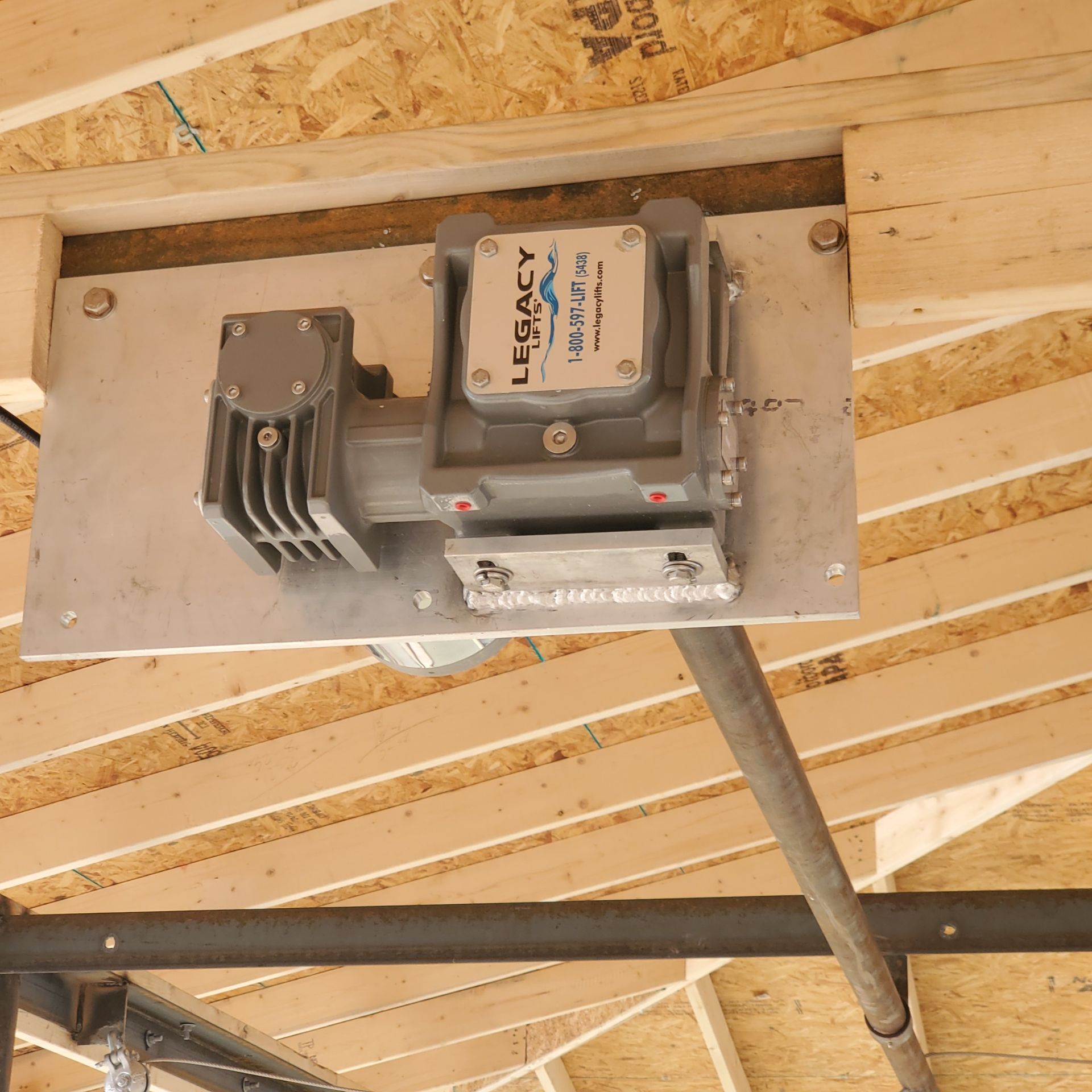 Electric boat lift mounted on a wooden wall inside a boat house.