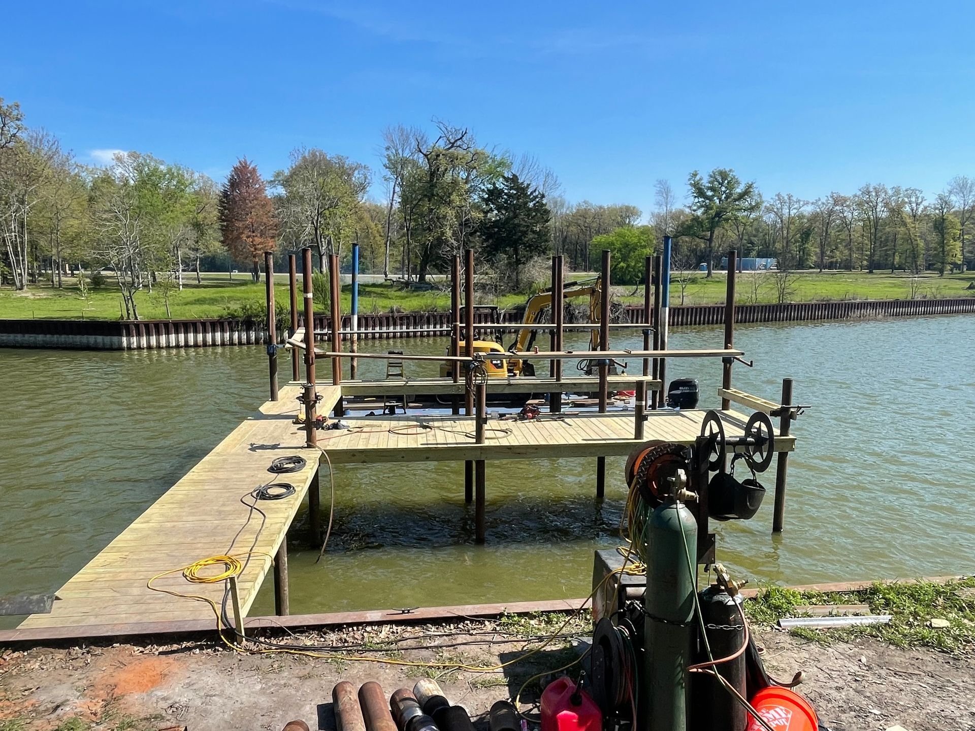 Small dock with metal equipment on a lake, under a clear blue sky, with trees in the background