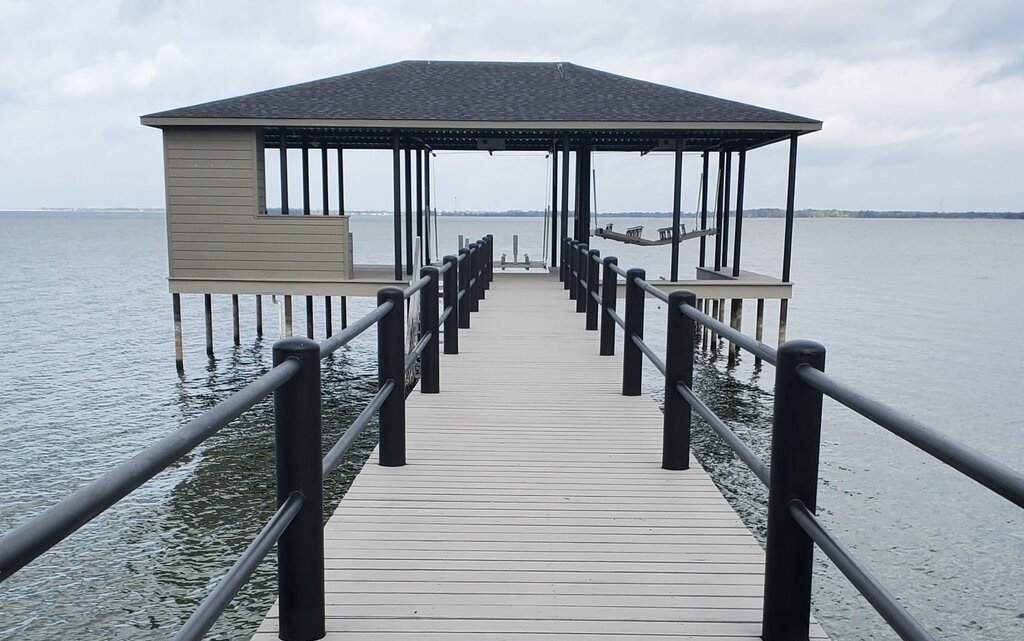 Wooden pier leading to a covered gazebo over calm water under a cloudy sky