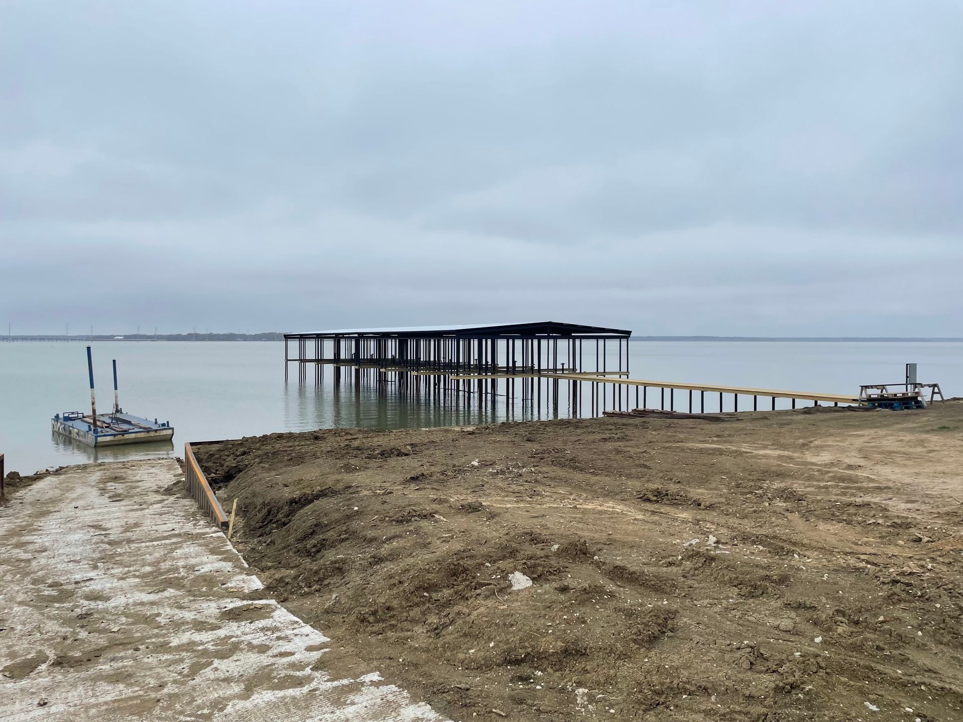 Overcast beach with a long wooden pier extending into calm water near a sandy shore