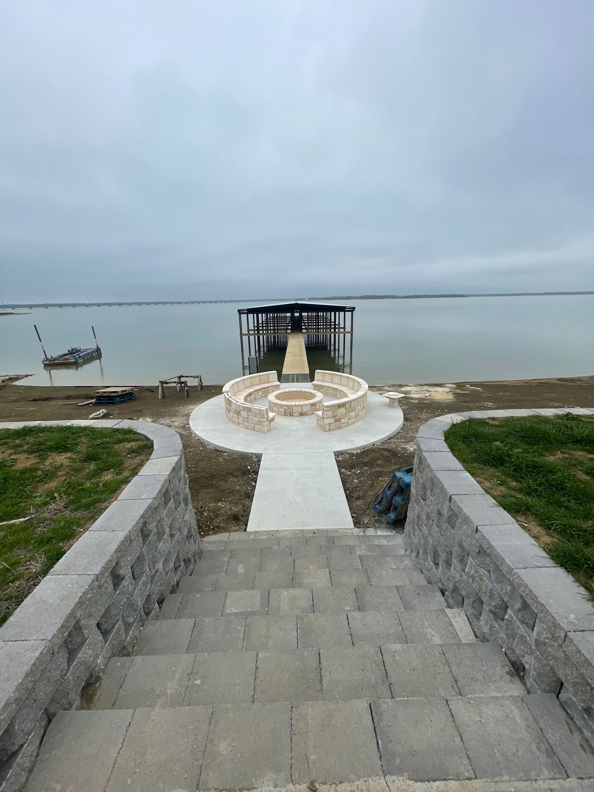 Stone steps leading to a seaside platform with a small canopy, under a cloudy sky