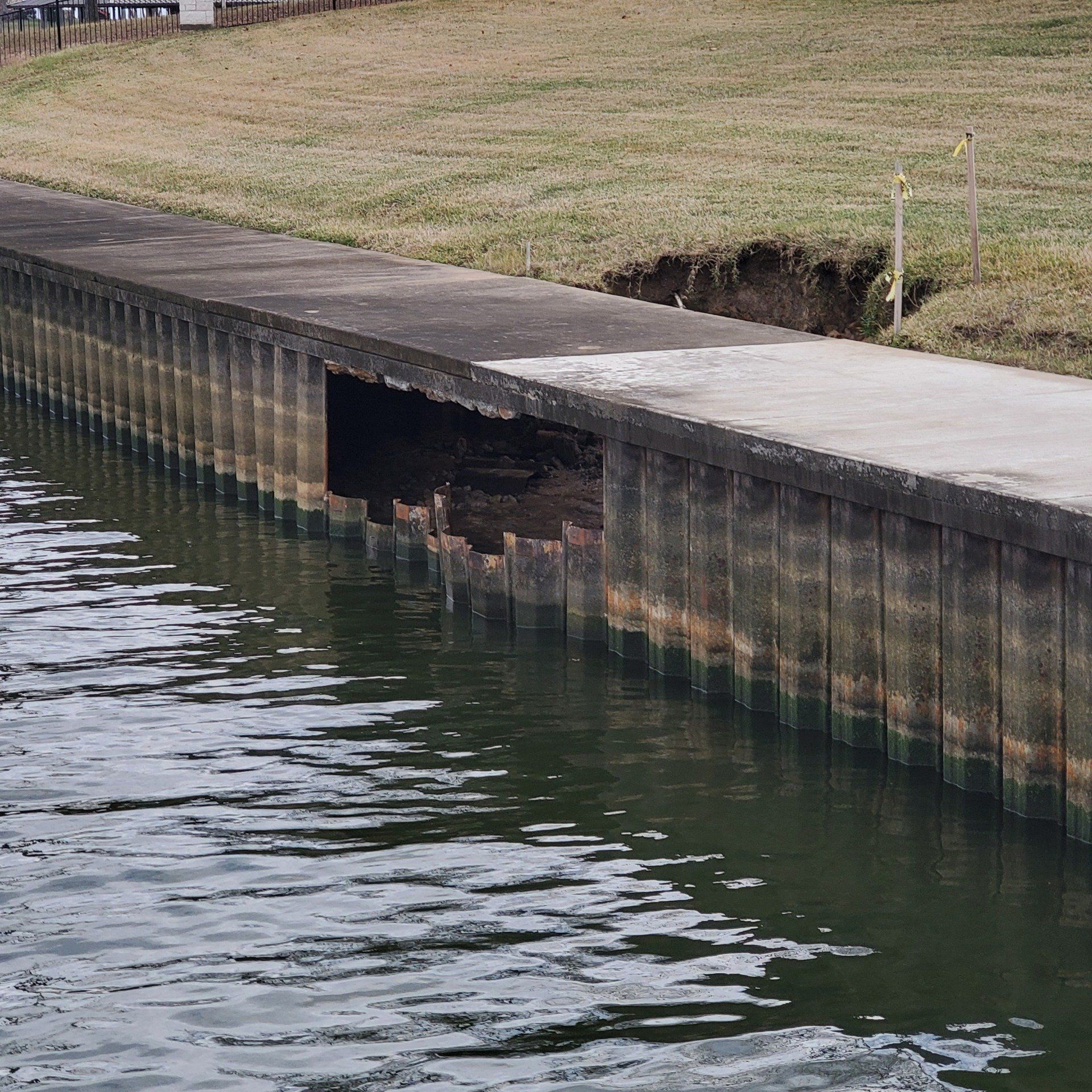 Damaged waterfront retaining wall with a large hole above the waterline
