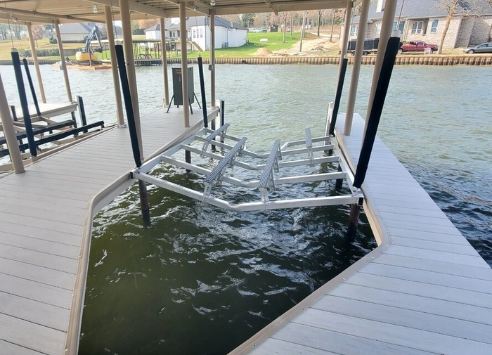 Broken metal dock lift hanging in water beside a covered lakeside dock