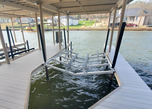 Covered boat lift dock beside a canal, with empty metal lift rails over dark water