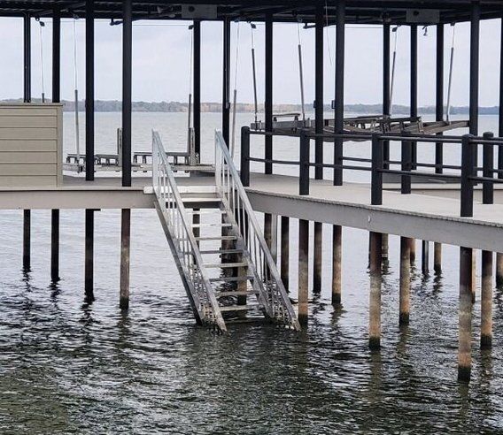 Waterfront dock with metal stairs descending into the water under a gray, overcast sky