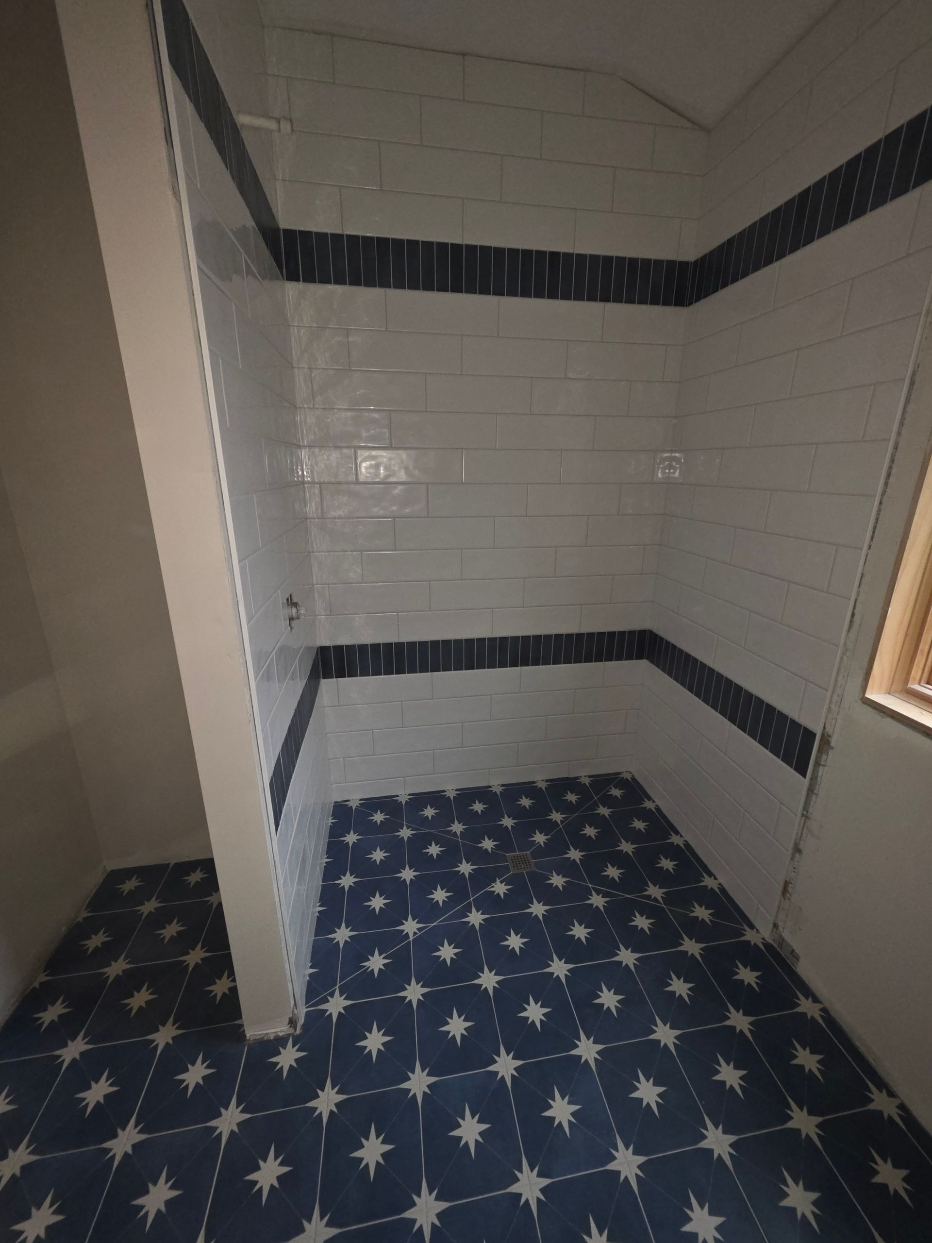 Person installing white floor tiles over gray adhesive with a trowel