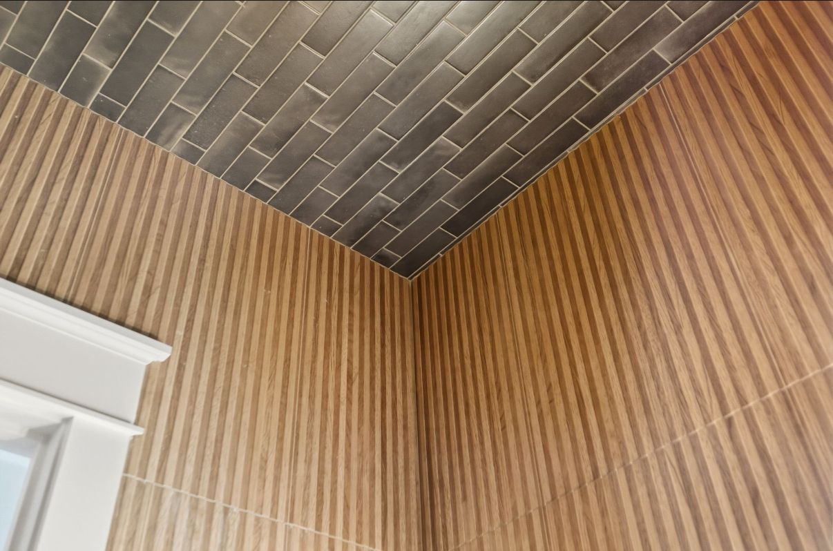 Hand spreading gray adhesive with a notched trowel on a wood floor surface