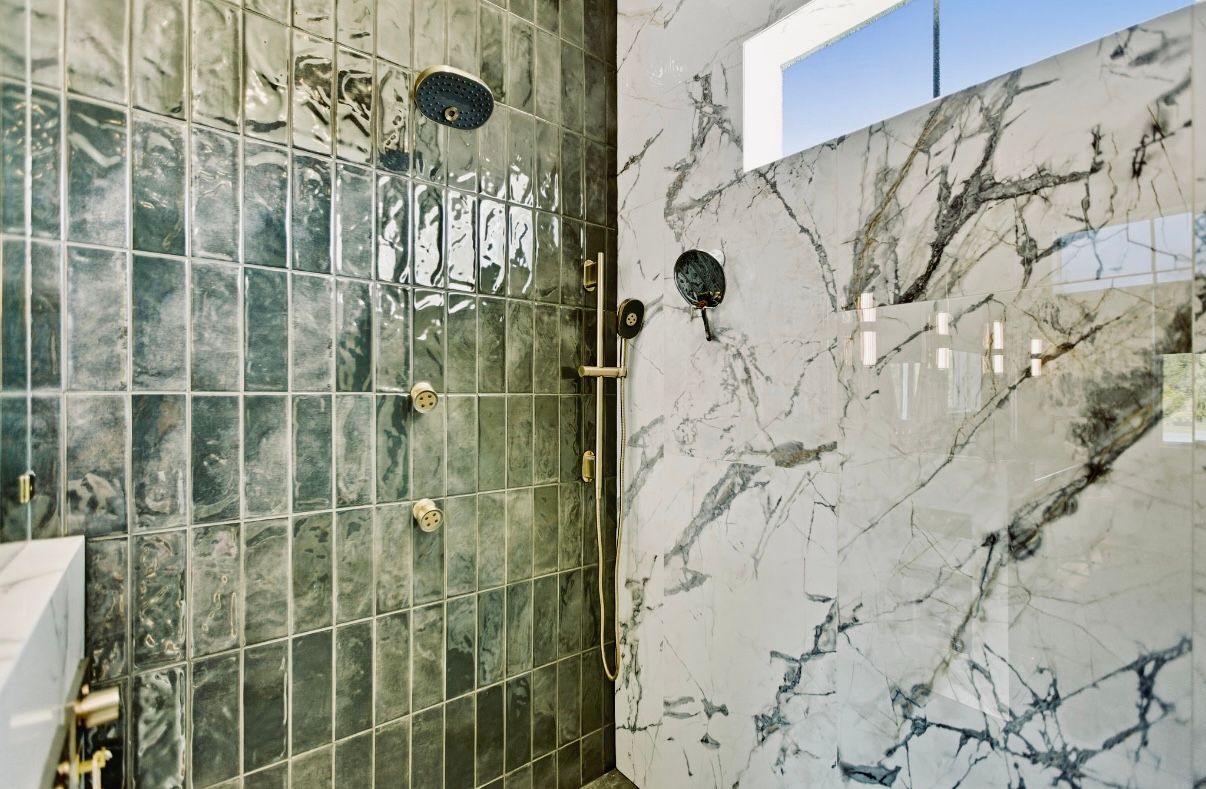 Stacked samples of patterned ceramic tiles in beige, terracotta, green, and gray tones