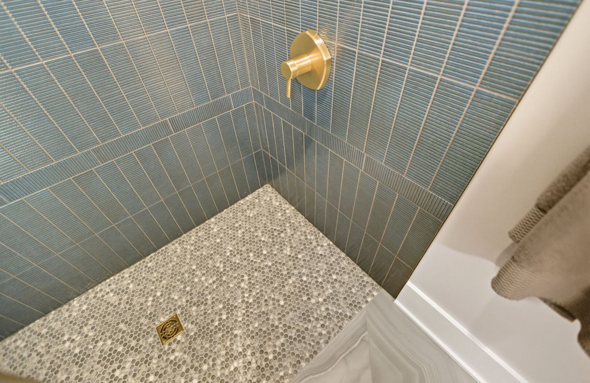 Hands arranging patterned hexagonal tiles on a floor beside a turquoise pool