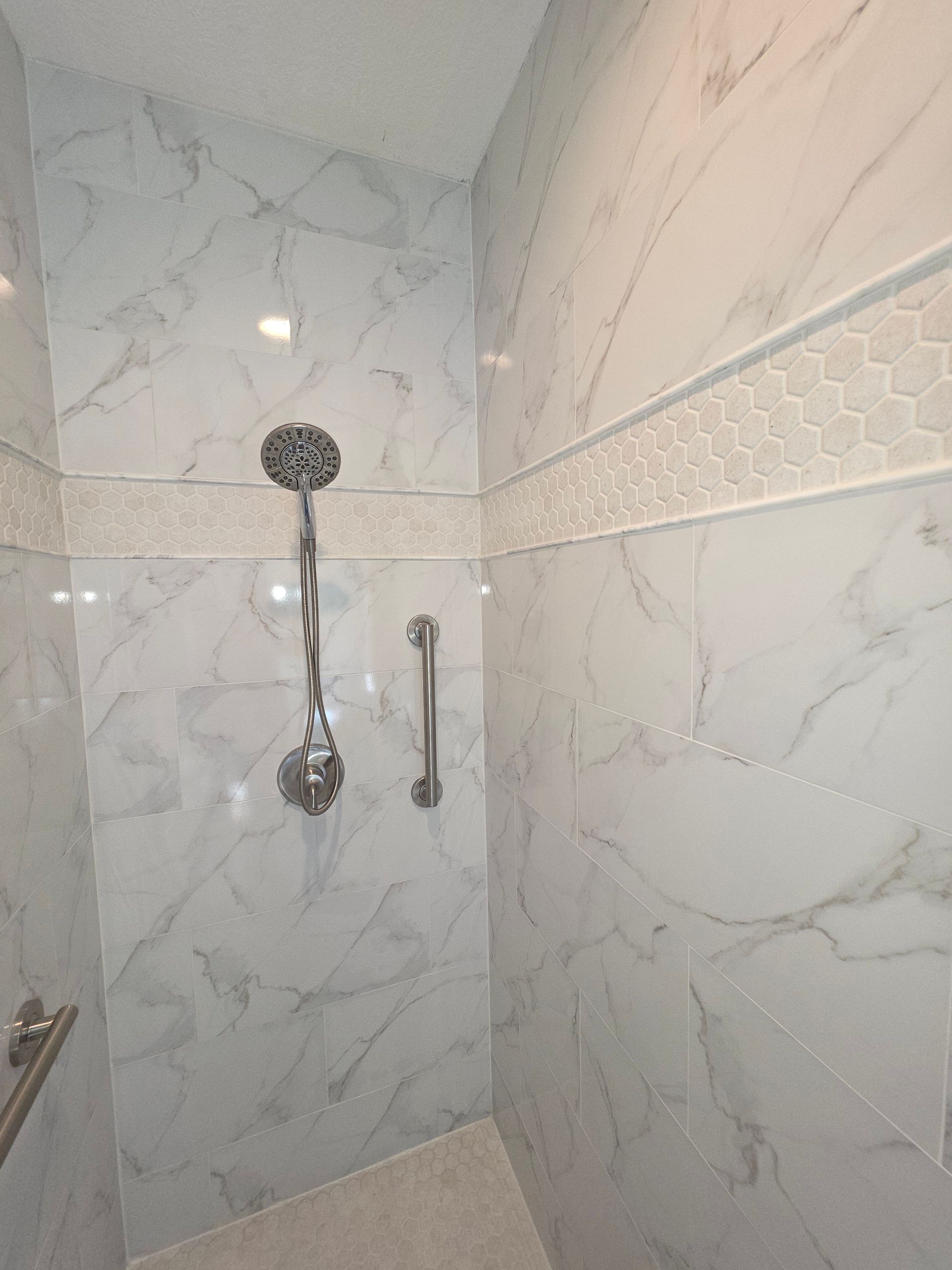 Modern bathroom with green tiled shower, double sink vanity, and black-and-white floor tiles