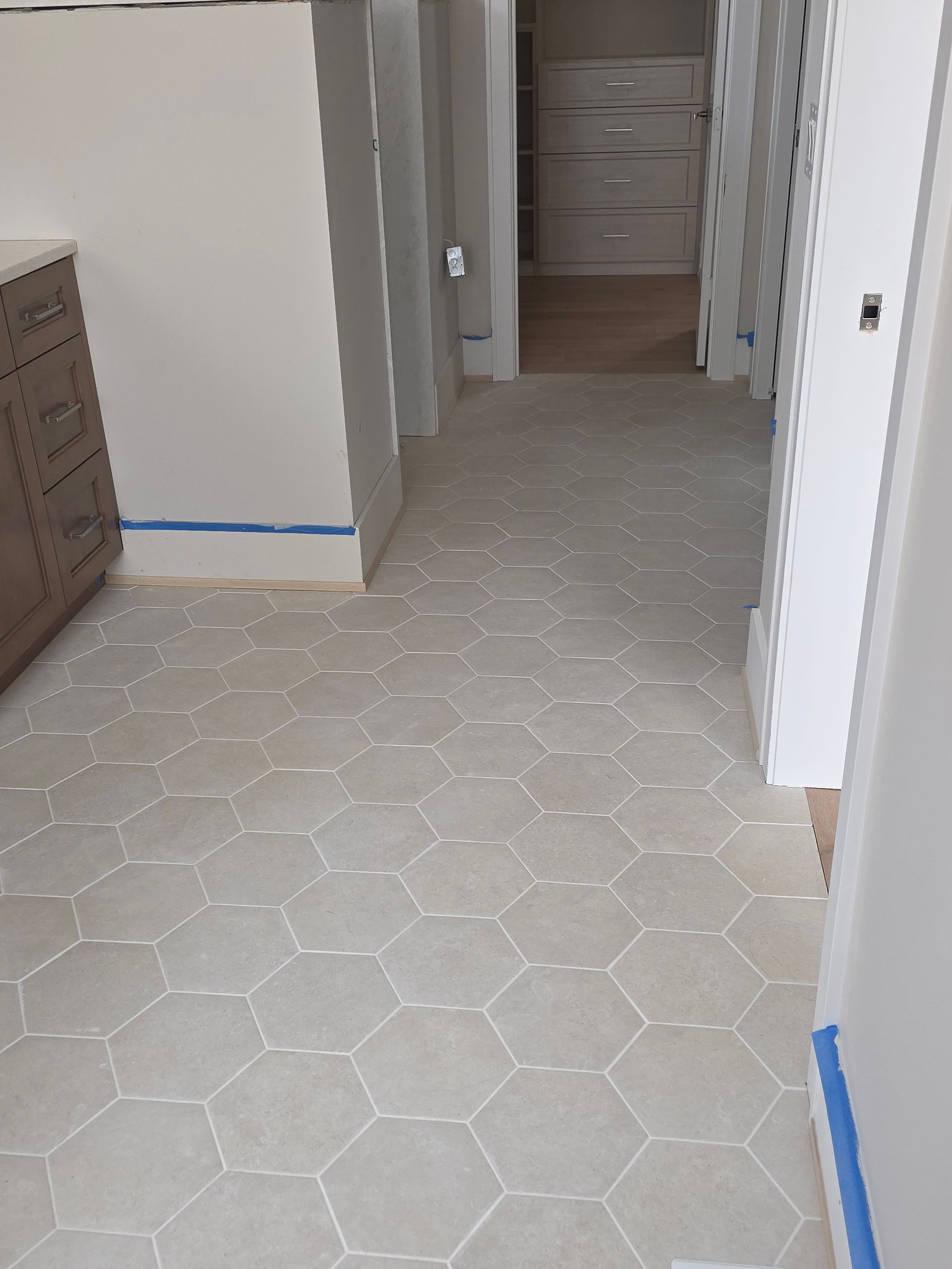 Hand using a power grinder to cut a white tile on a floor surface