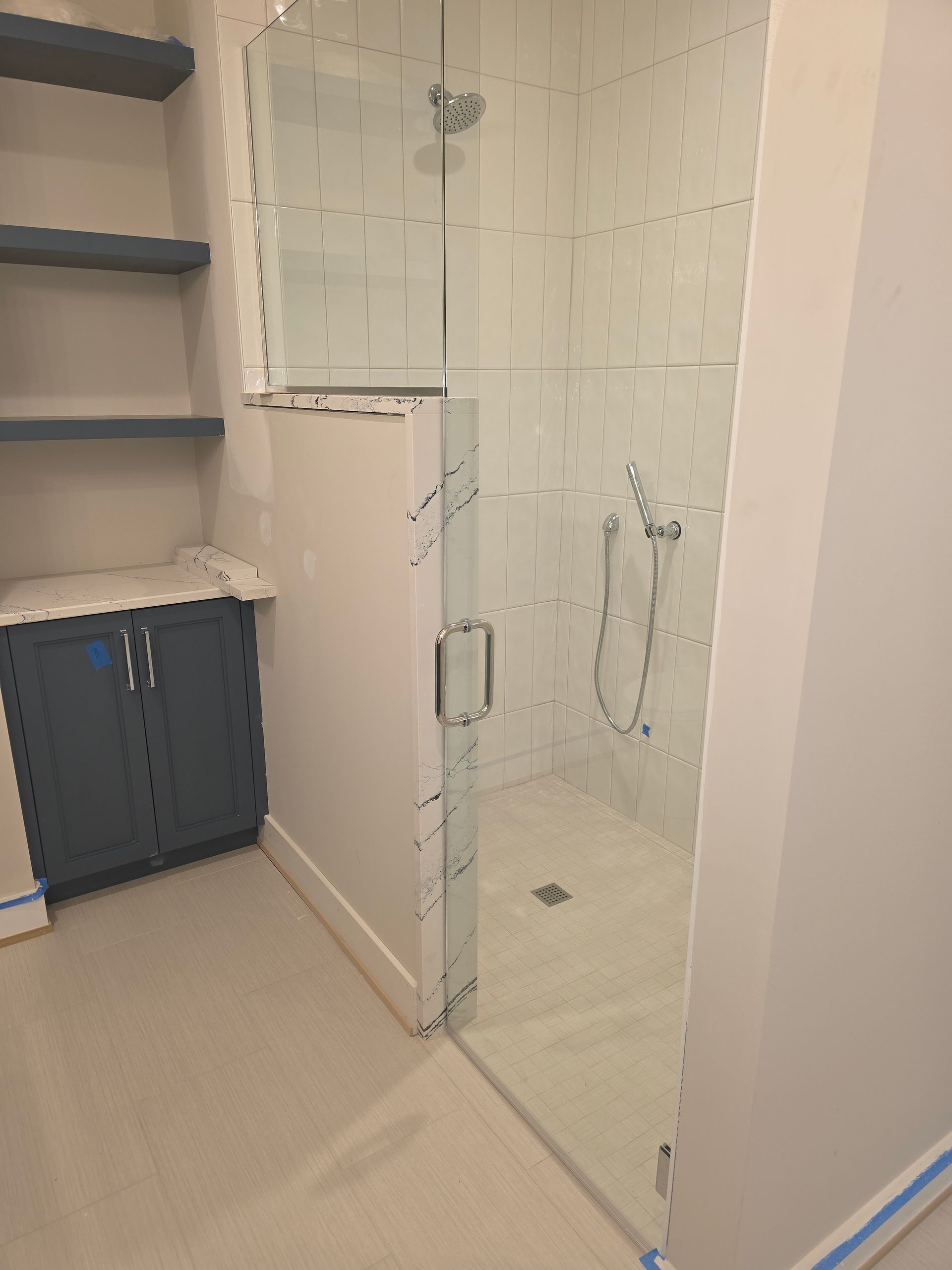 Modern marble bathroom with glass shower, freestanding tub, and window view of trees