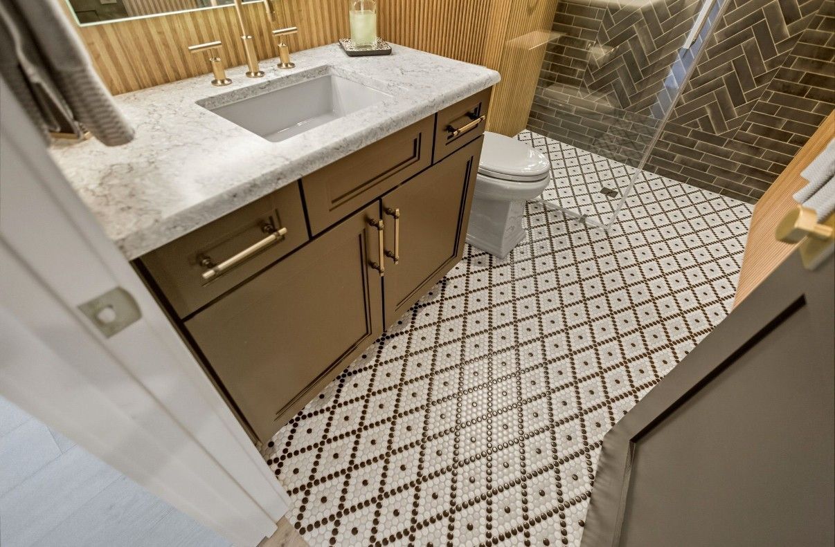 Walk-in shower with marble-look tile walls, pebble floor, and a white door partially open