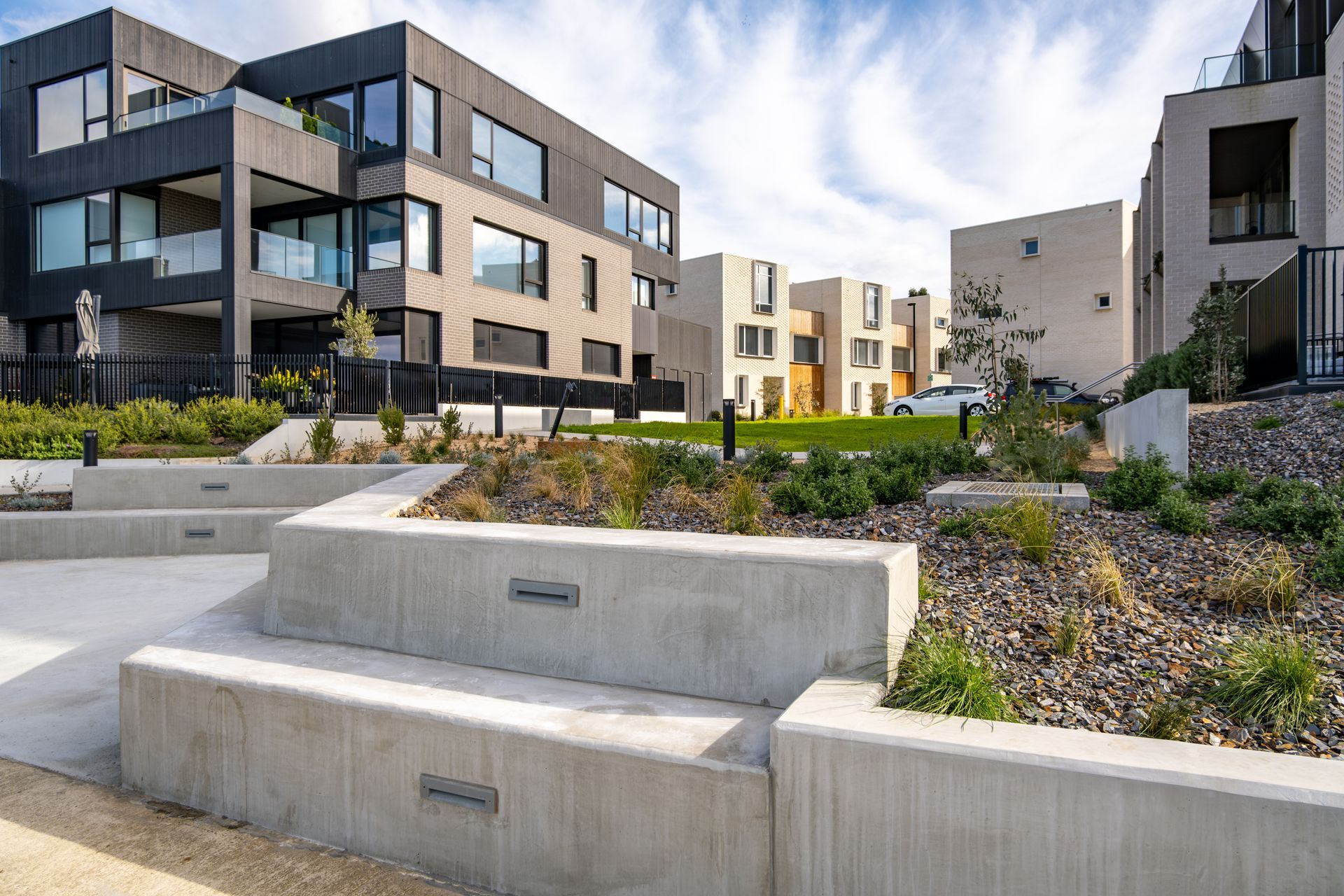 Modern apartment courtyard with concrete terraces, low shrubs, and contemporary buildings under a bright sky Modern apartment courtyard with concrete terraces, low shrubs, and contemporary buildings under a bright sky