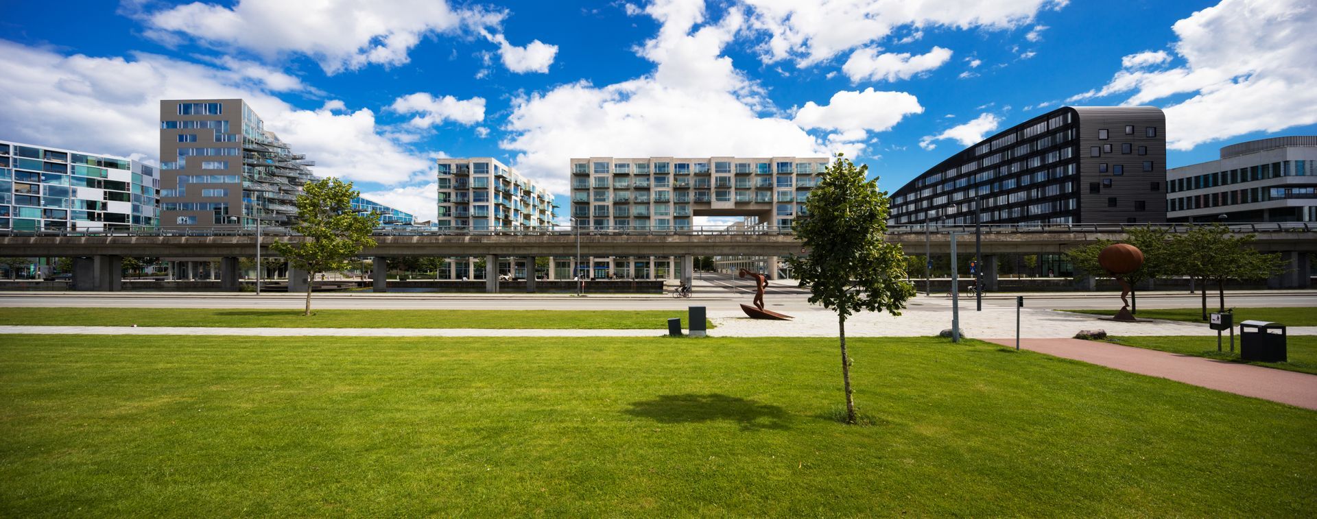 Modern campus buildings behind a wide green lawn under a blue sky Modern campus buildings behind a wide green lawn under a blue sky