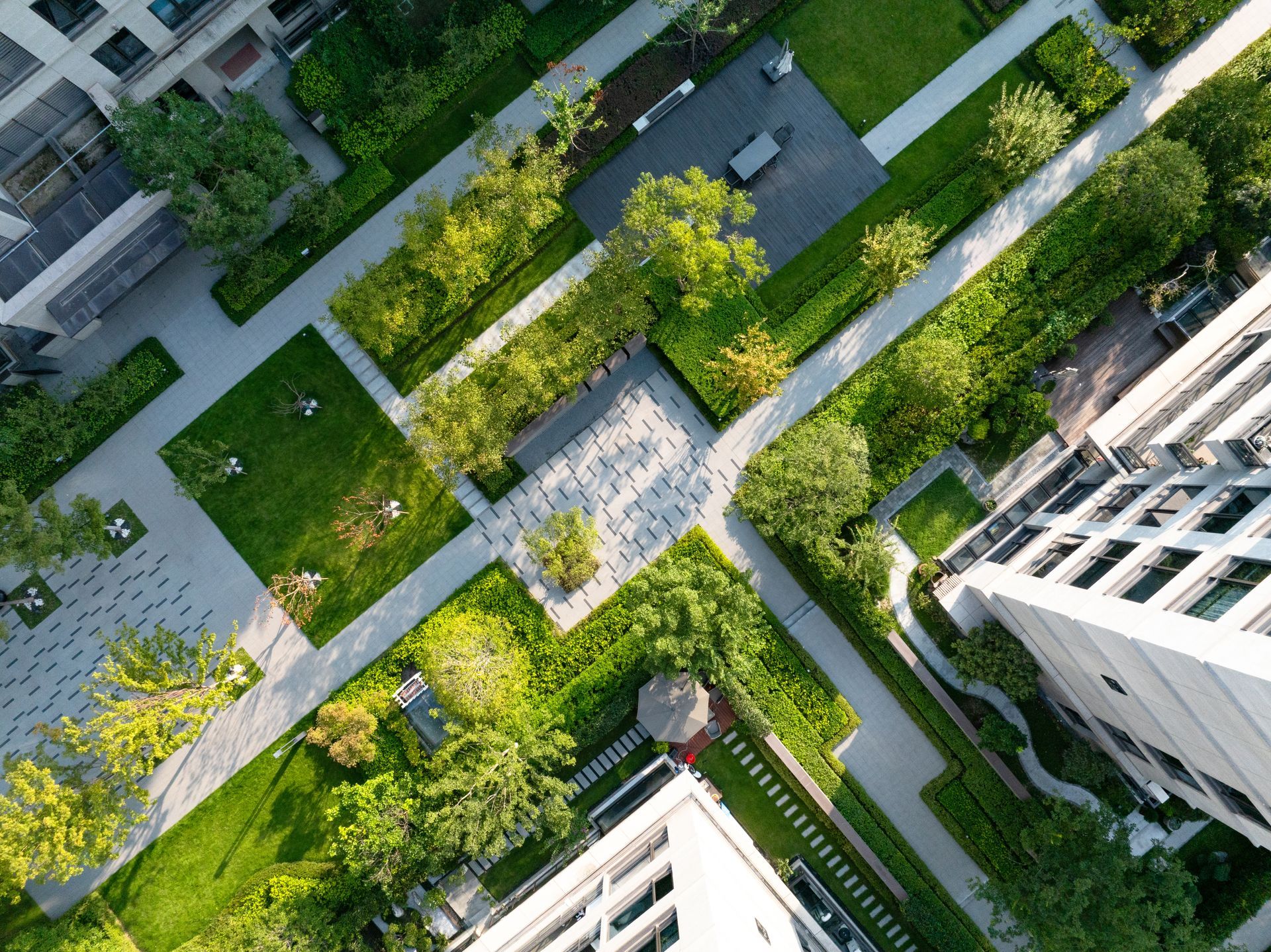 Aerial view of a landscaped courtyard with walkways, grass, trees, and surrounding apartment buildings. Aerial view of a landscaped courtyard with walkways, grass, trees, and surrounding apartment buildings.