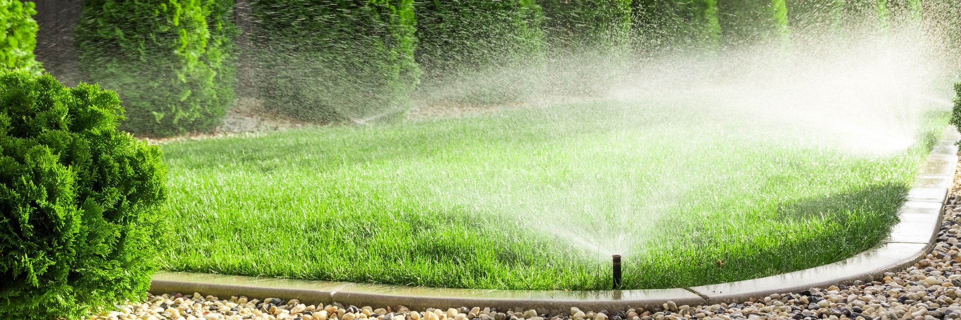 Landscape technician checking an irrigation system in a green lawn area