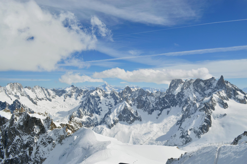 Chaîne de montagnes enneigées sous un ciel bleu partiellement nuageux.