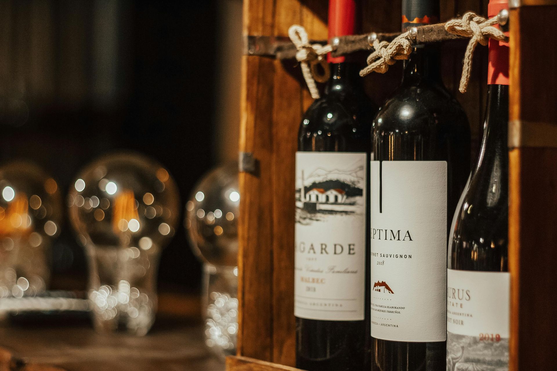 Bouteilles de vin dans une caisse en bois avec des ampoules décoratives au premier plan.