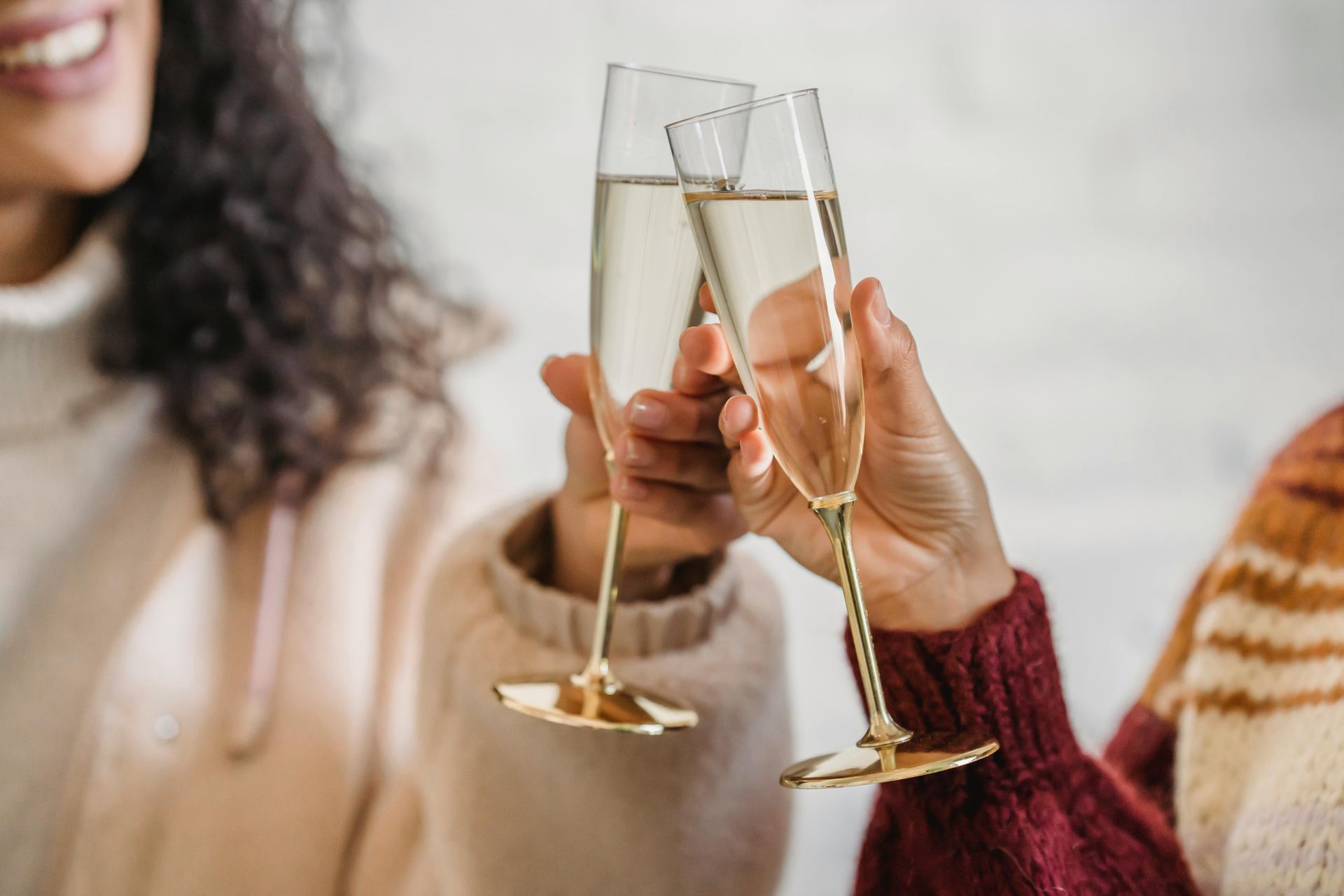Deux personnes qui trinquent avec des flûtes de champagne, vêtues de pulls.