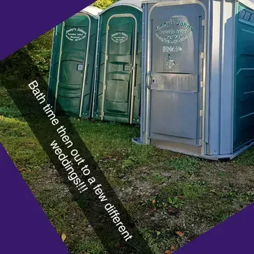 A row of portable toilets are lined up in the grass.