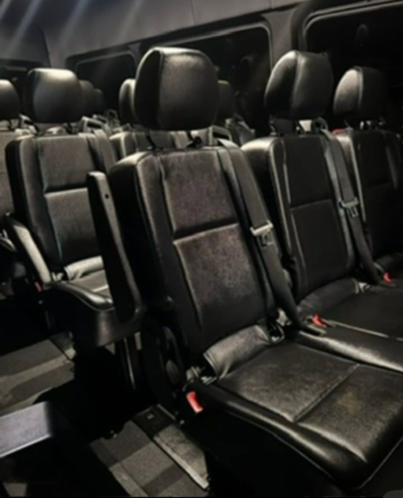 Rows of black leather seats inside a van or shuttle bus