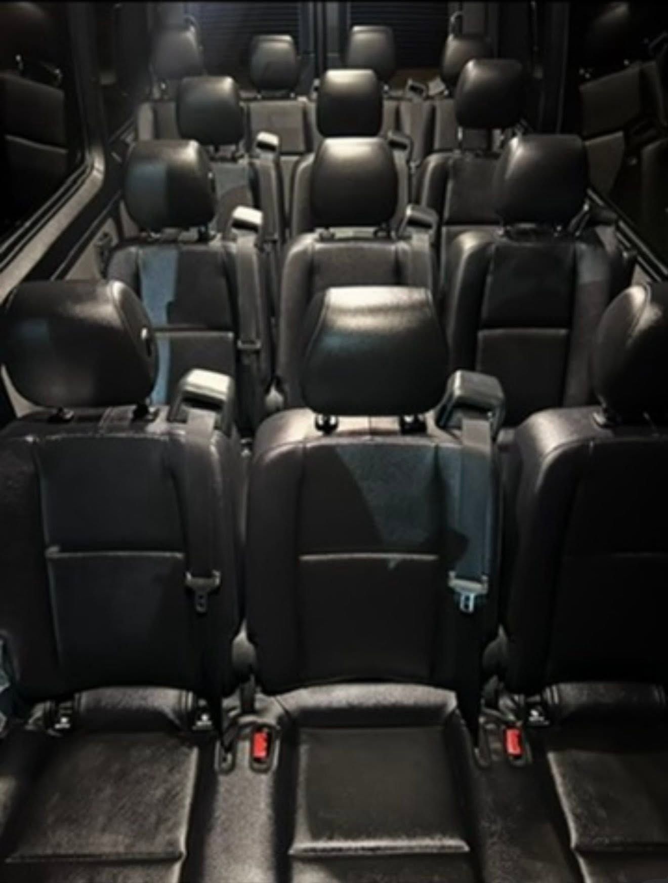 Empty row of black leather seats in a vehicle interior, viewed from the rear.