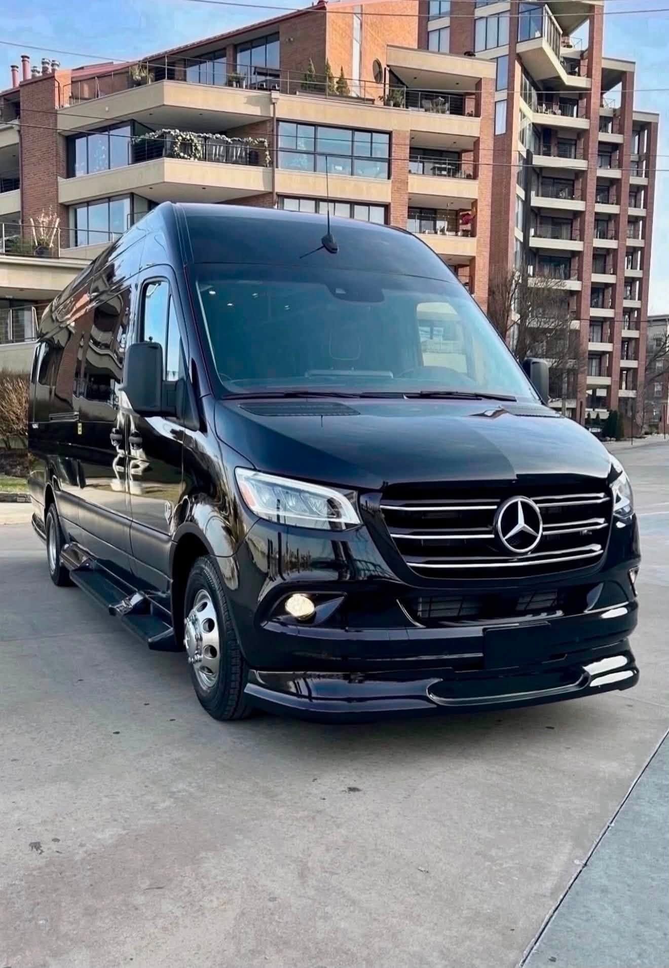 Black Mercedes van parked on a city street with modern apartment buildings in the background