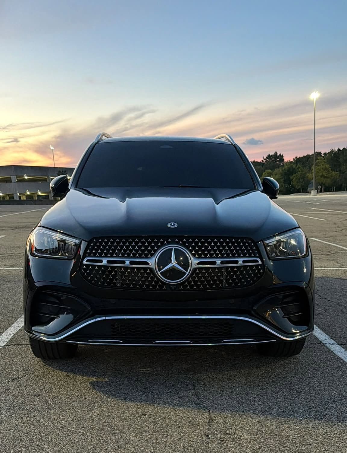 Black Mercedes SUV parked in a lot at sunset, front view.