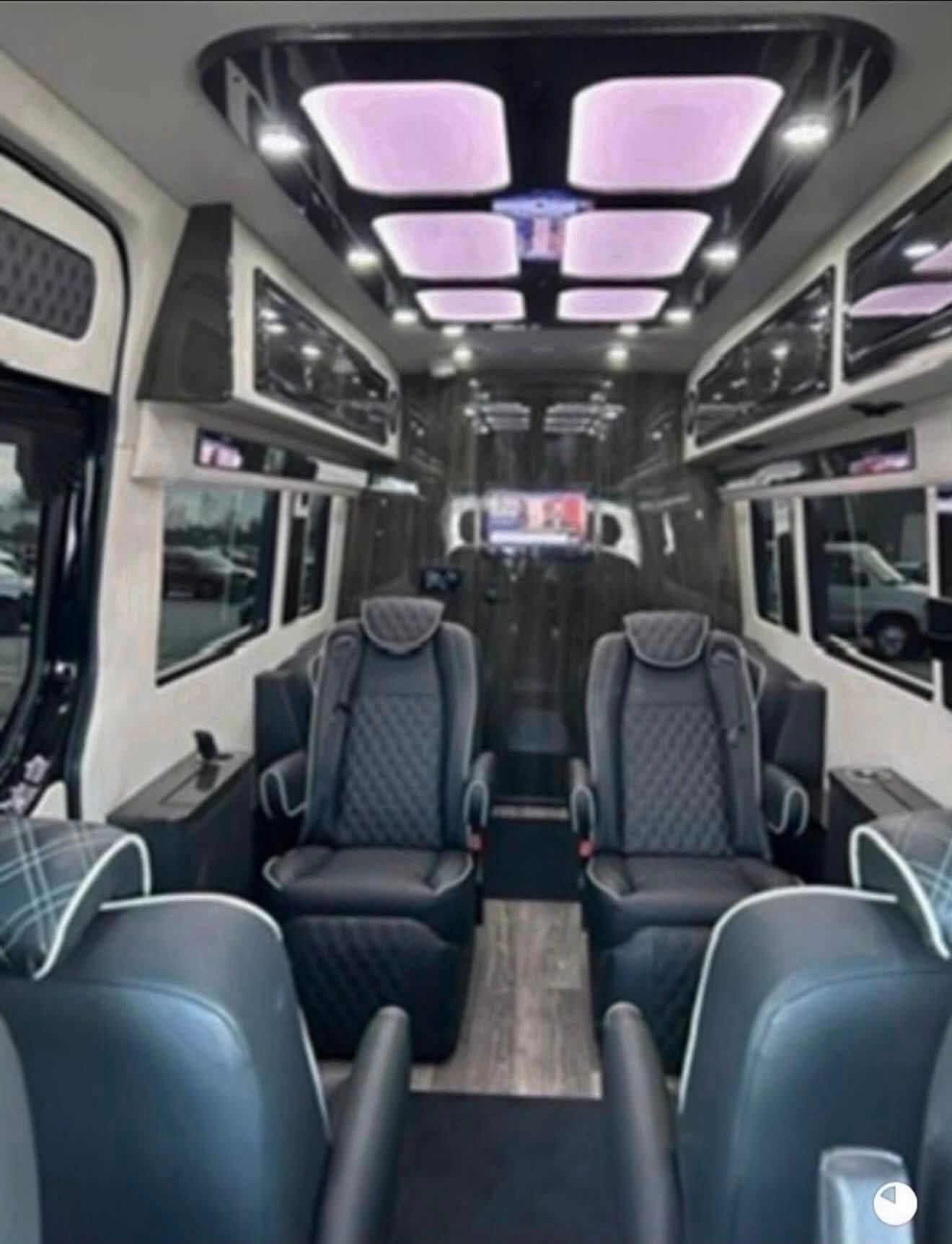 Modern van interior with four gray leather seats and purple ceiling lights
