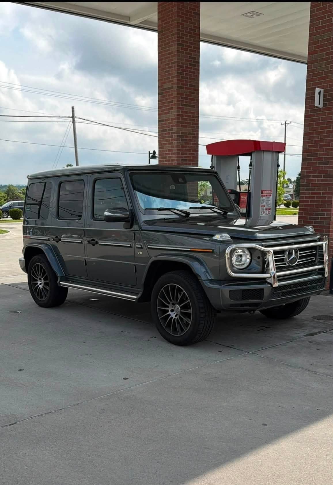 Dark gray SUV parked at a gas station under a canopy near a red-and-white pump.
