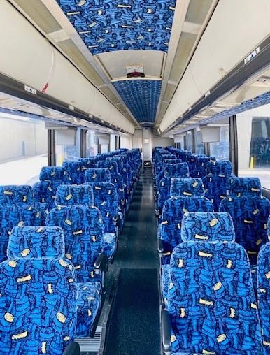 Empty train carriage with rows of blue patterned seats and overhead luggage racks
