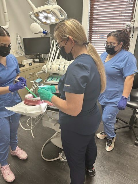 two dentists are examining a patient 's teeth in a dental office .