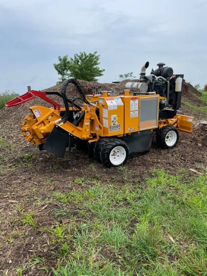 Orange industrial machine with a red arm in a muddy field under an overcast sky