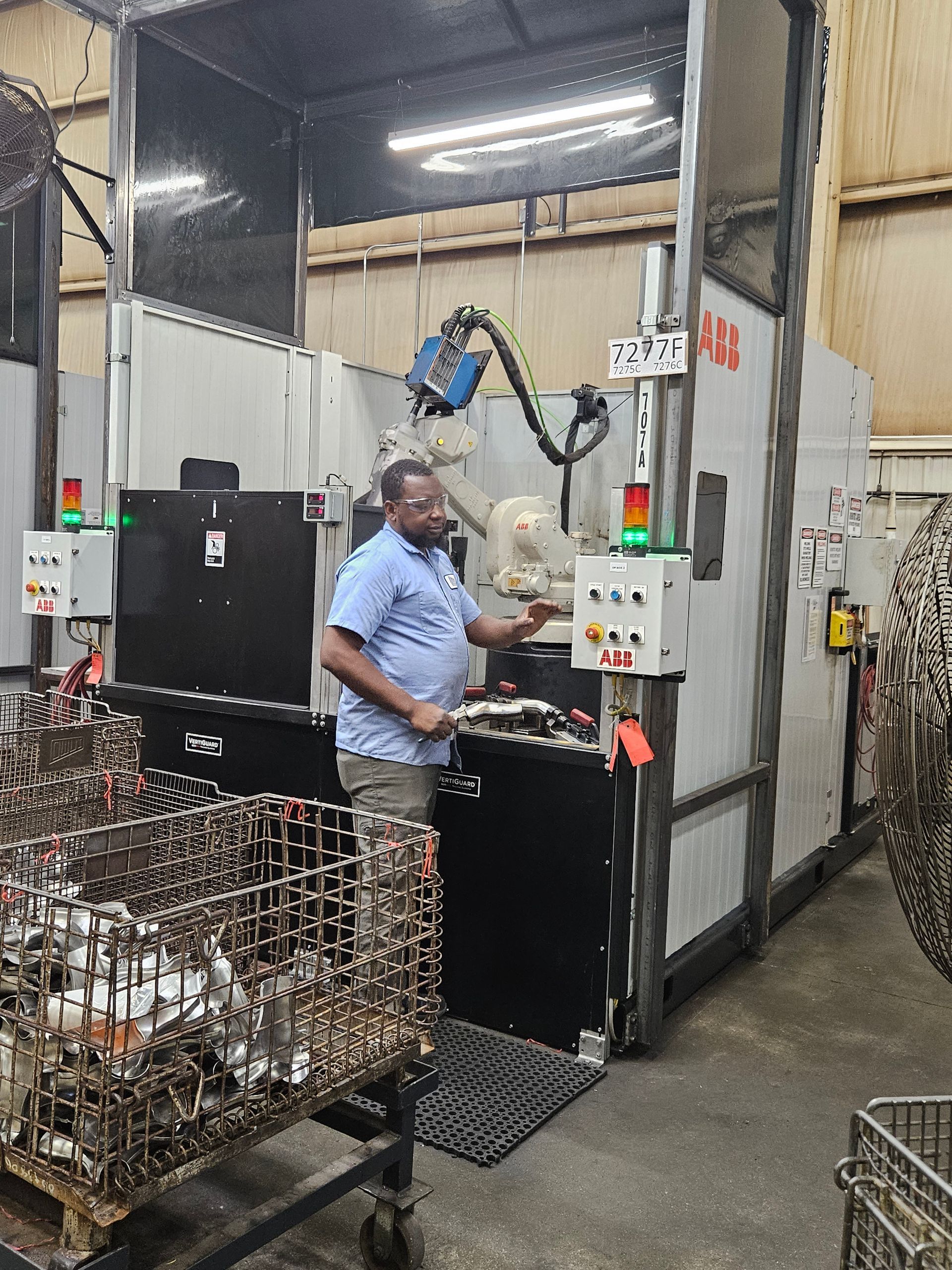 A man is standing in front of a machine in a factory.