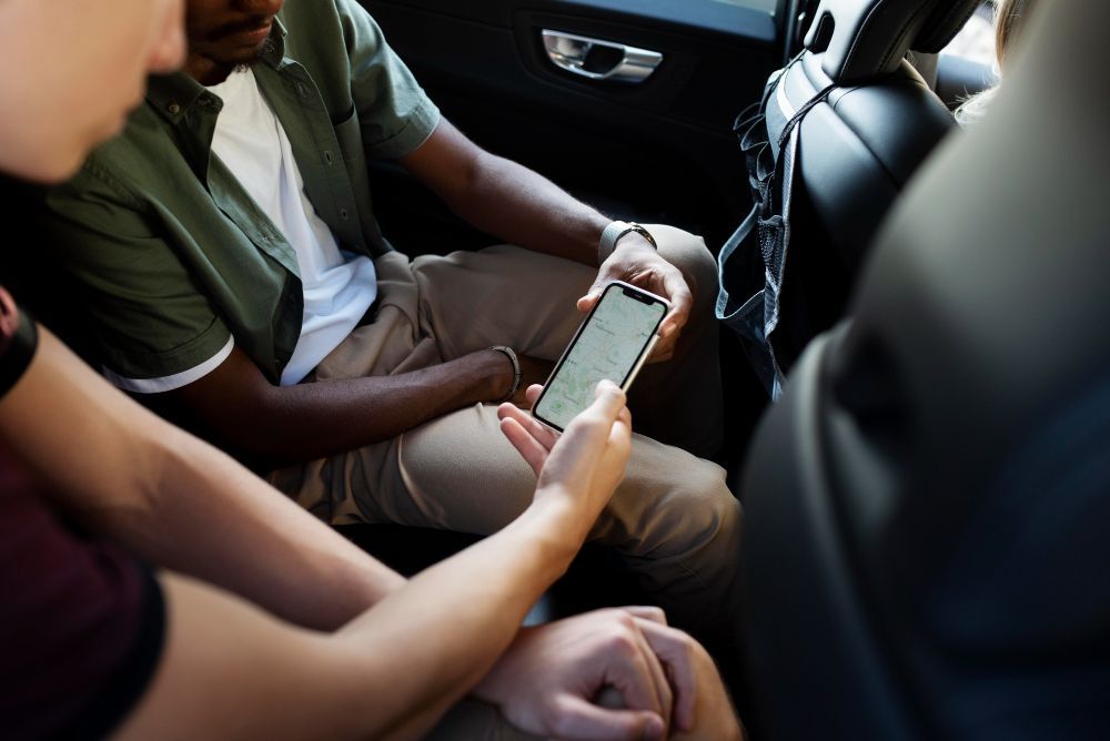 Two people in a car looking at a smartphone screen.
