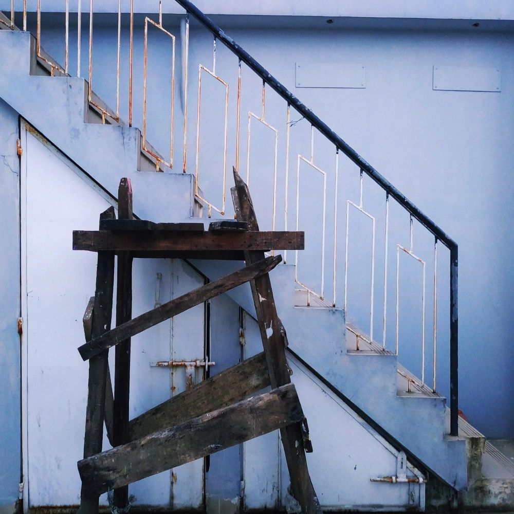 Wooden scaffolding in front of a blue staircase with a metal railing.