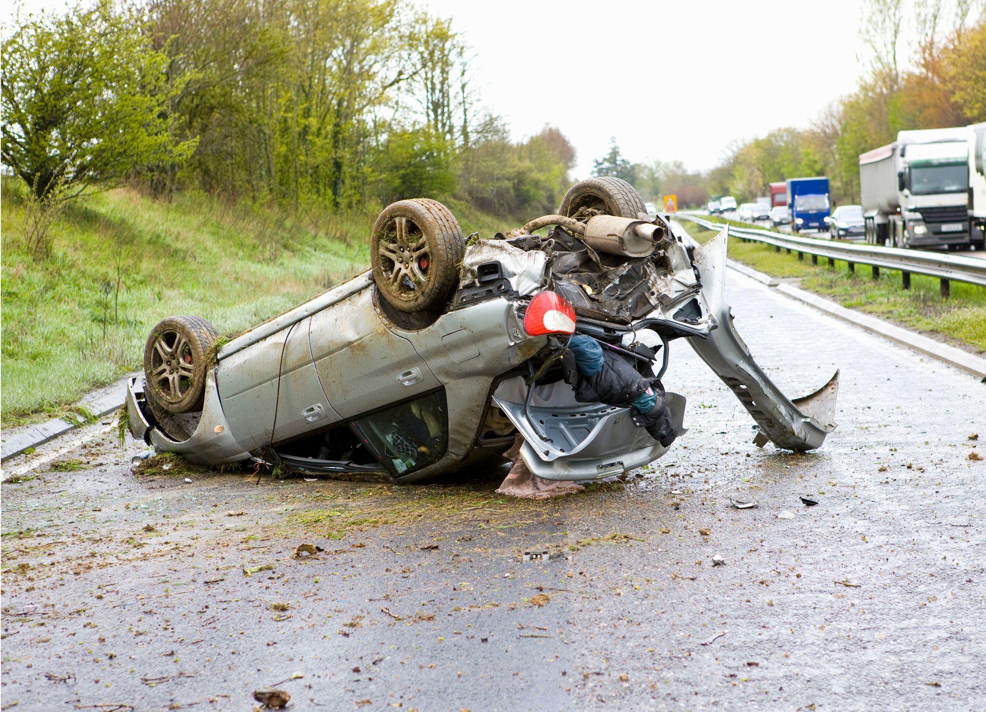 Overturned car on highway; wreckage visible.