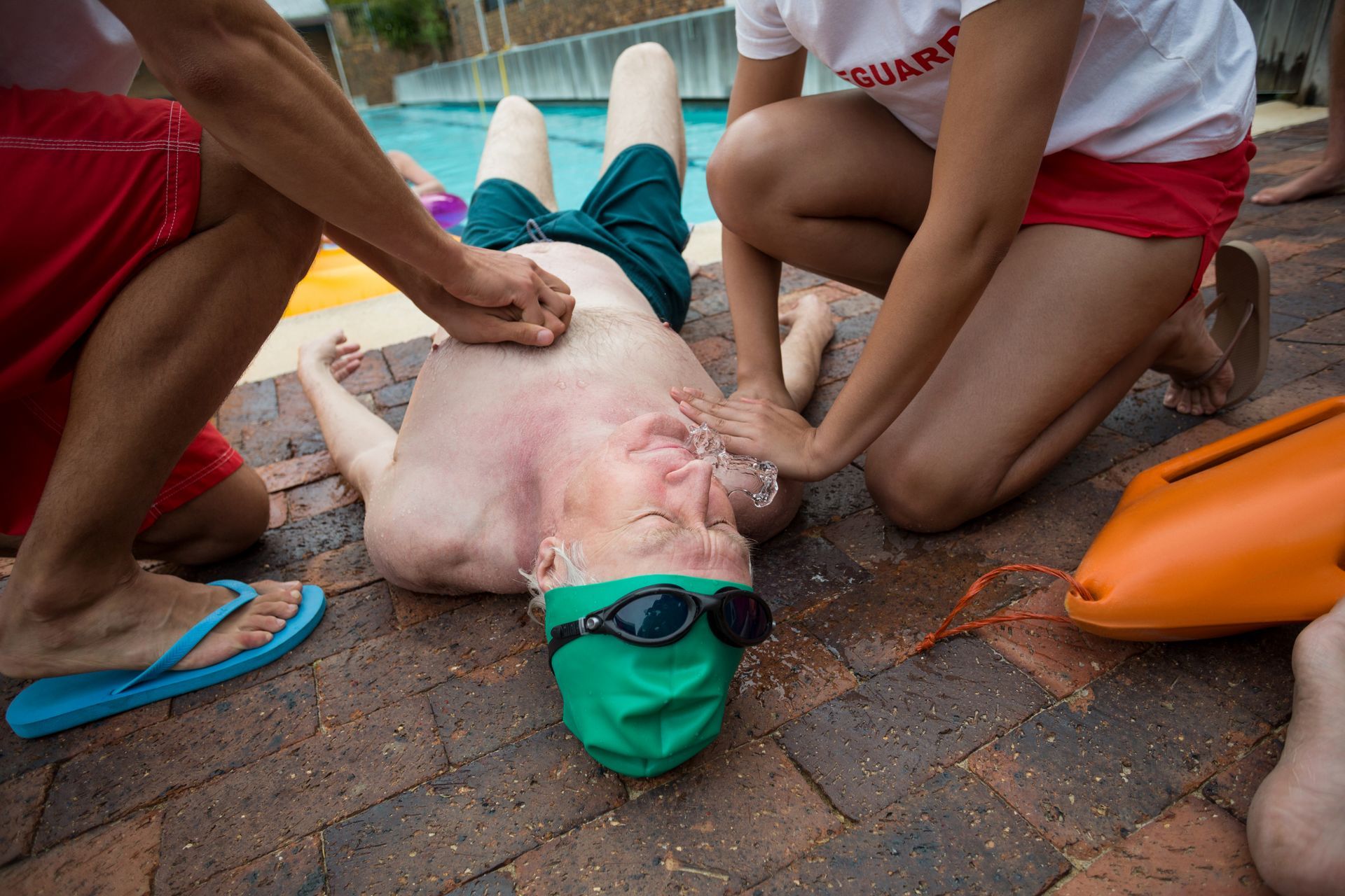 Lifeguards performing CPR on a person at a pool.