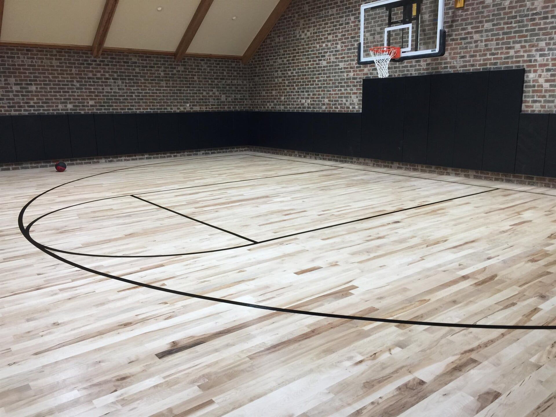 A basketball court with a wooden floor and a brick wall.