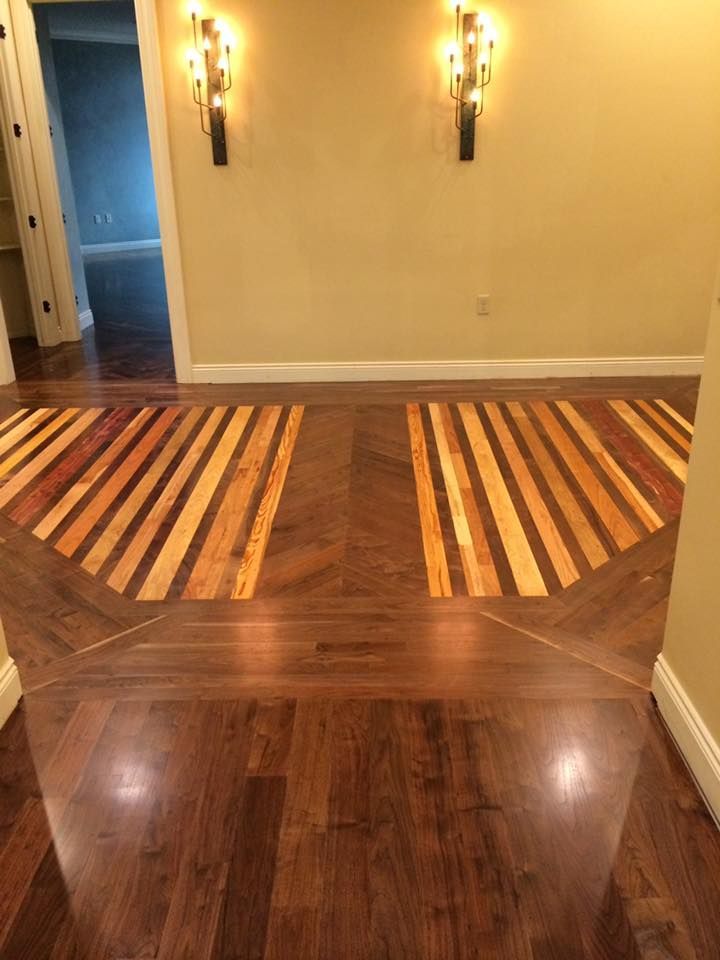 A hallway with a wooden floor and two candles on the wall.