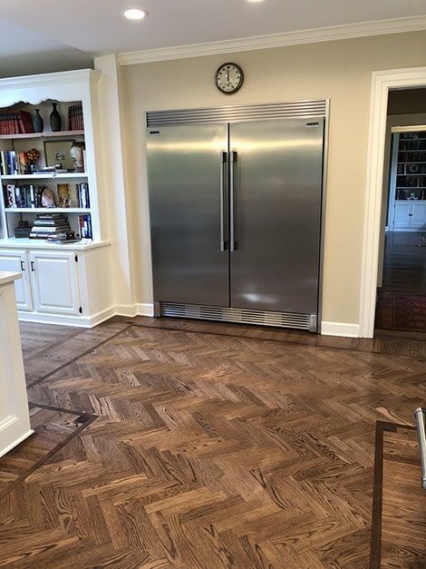 A kitchen with a stainless steel refrigerator and a clock on the wall.